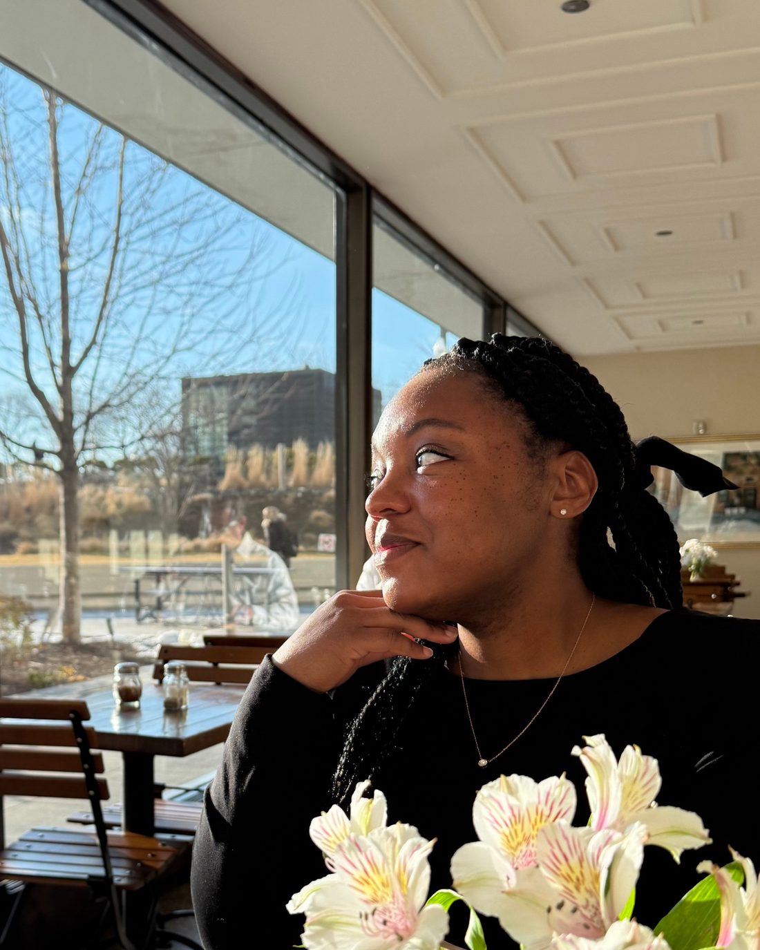 Dr. Tamara Starling smiling by a sunny cafe window with white flowers